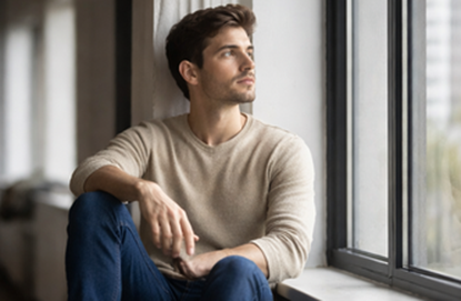man sitting by window reflecting on stress and internal emotional state