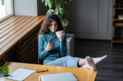 Woman avoiding work by using phone while procrastinating instead of completing tasks