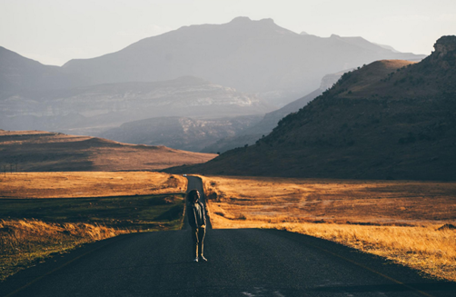 person walking alone on empty road symbolizing leaving comfort zone and facing change