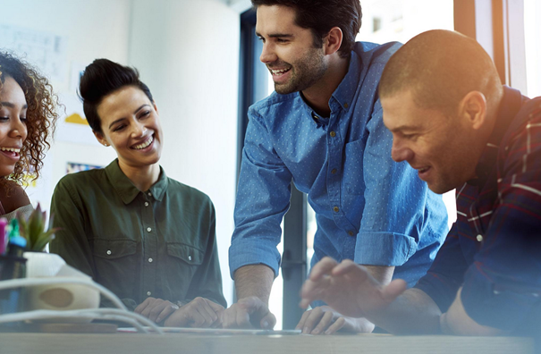 Four coworkers smiling and collaborating around a table.