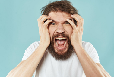 Bearded man gripping his head and shouting in frustration