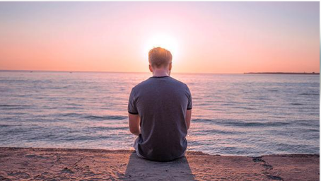 Man looking at the ocean while reflecting on his thoughts
